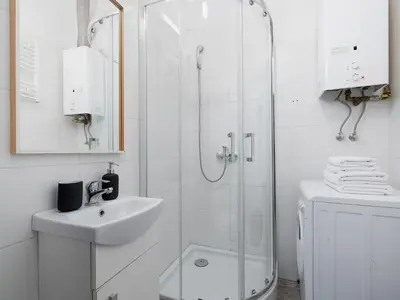 a white bathroom with a shower and a sink at 1-bedroom apartment - Długa 65 street in Kraków