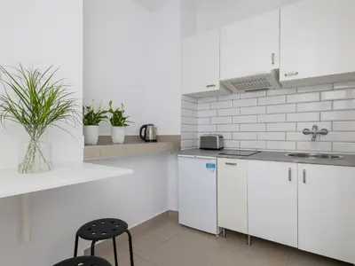 a white kitchen with white cabinets and a sink at 1-bedroom apartment - Długa 65 street in Kraków