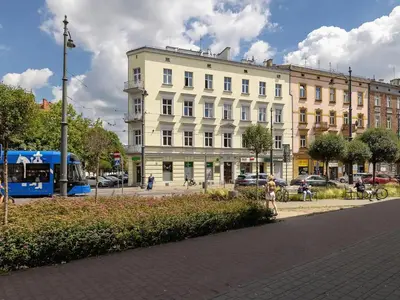 a large white building on a city street with a bus at 1-bedroom apartment - Długa 65 street in Kraków