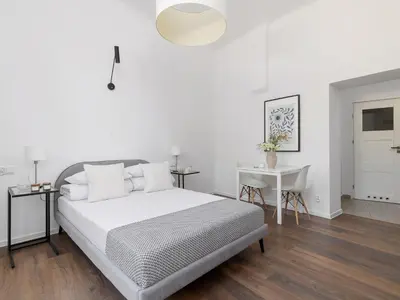 a white bedroom with a bed and a table at 1-bedroom apartment - Długa 65 street in Kraków