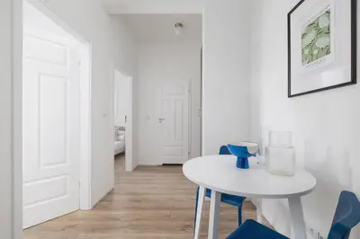 a white dining room with a white table and blue chairs at 2 Bedroom Apartment - Długa 65 in Kraków