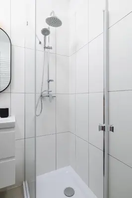 a white bathroom with a shower with a glass door at 2 Bedroom Apartment - Długa 65 in Kraków
