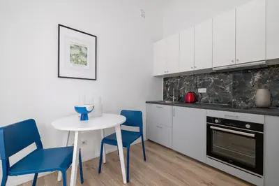 a kitchen with white cabinets and a table and chairs at 2 Bedroom Apartment - Długa 65 in Kraków