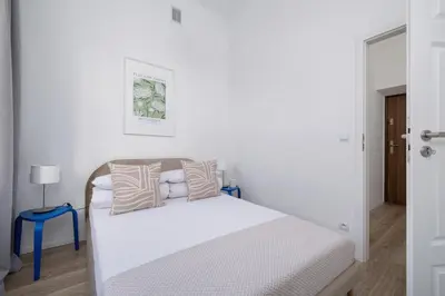 a white bedroom with a bed and a blue stool at 2 Bedroom Apartment - Długa 65 in Kraków
