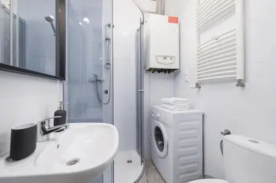 a white bathroom with a sink and a washing machine at 1-Bedroom Apartment - Długa 65 Street in Kraków