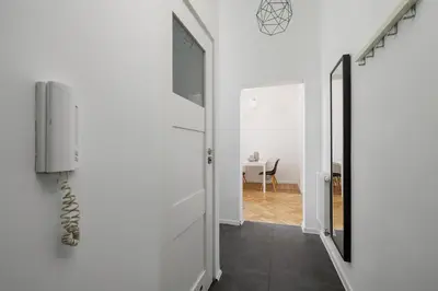 a hallway with white walls and a door and a table at 2-Bedroom Apartment with Balcony - Długa 65 in Kraków