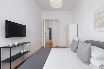 a white bedroom with a bed and a flat screen tv at 2-Bedroom Apartment with Balcony - Długa 65 in Kraków