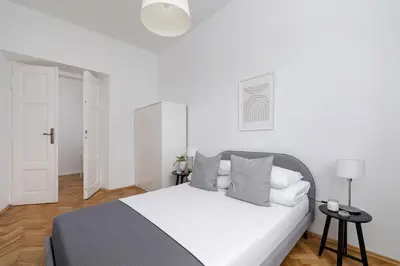 a white bedroom with a white bed with gray pillows at 2-Bedroom Apartment with Balcony - Długa 65 in Kraków