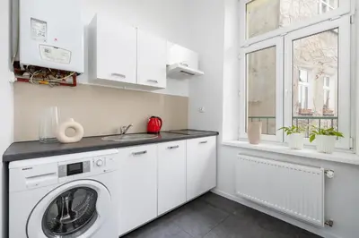 a white laundry room with a washer and a window at 2-Bedroom Apartment with Balcony - Długa 65 in Kraków