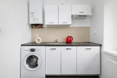 a white kitchen with a washing machine and a sink at 2-Bedroom Apartment with Balcony - Długa 65 in Kraków