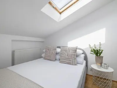 a white bedroom with a bed and a skylight at Studio apartment with AC - Długa 65 street in Kraków