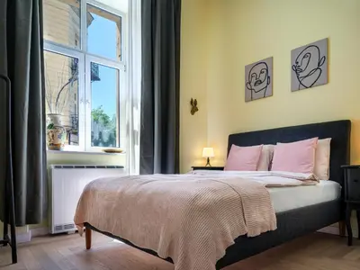 a bedroom with a bed with pink pillows and a window at Yellow Studio - Kochanowskiego in Kraków