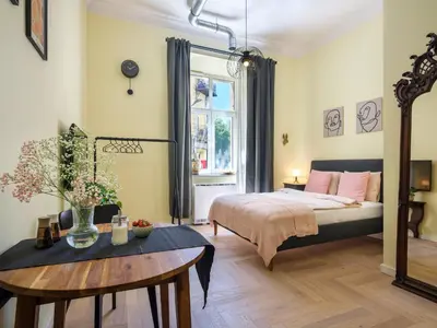 a bedroom with a bed and a table and a window at Yellow Studio - Kochanowskiego in Kraków