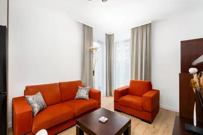 a living room with an orange couch and a chair at Przewóz Comfort Apartment by BookingHost in Kraków
