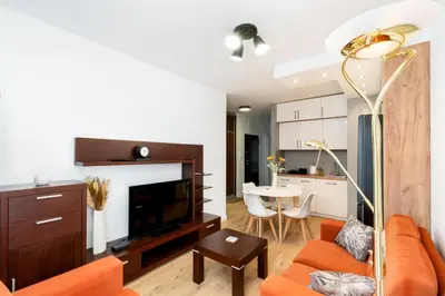 a living room with an orange couch and a table at Przewóz Comfort Apartment by BookingHost in Kraków