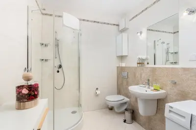 a white bathroom with a shower and a toilet and a sink at Przewóz Comfort Apartment by BookingHost in Kraków