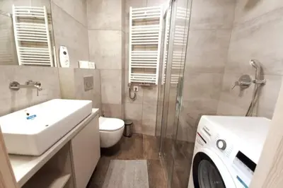 a bathroom with a toilet and a sink and a washing machine at Old Town Apartments - Kącik 60 in Kraków