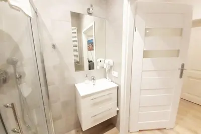 a white bathroom with a sink and a shower at Old Town Apartments - B42 in Kraków