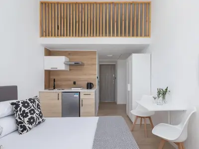 a bedroom with a white bed and a kitchen at Studio Apartment - Radziwiłłowska 27 in Kraków