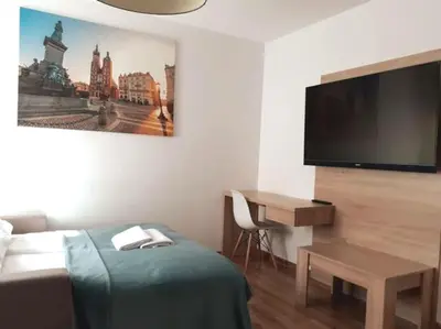 a hotel room with a bed and a desk and a flat screen tv at Old Town Apartments - B22 in Kraków
