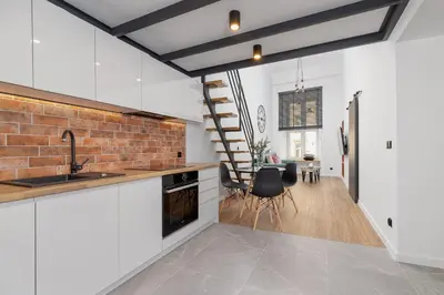 a kitchen with white cabinets and a brick wall at Modern Apartment in Kazimierz District - Józefa 2 in Kraków
