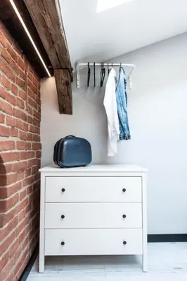 a bedroom with a white dresser and a brick wall at Studio for two with an AC - Dietla 51 street in Kraków