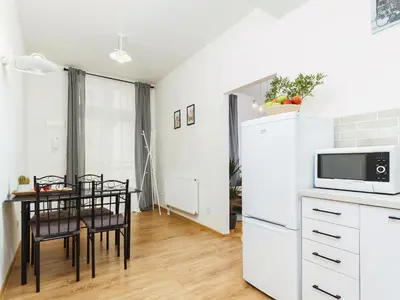 a kitchen with a table and a white refrigerator at 1 Bedroom Apartment - Starowiślna 54 in Kraków