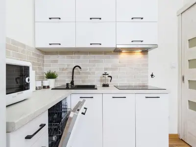 a white kitchen with white cabinets and a microwave at 1 Bedroom Apartment - Starowiślna 54 in Kraków