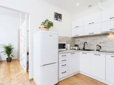 a white kitchen with white cabinets and a refrigerator at 1 Bedroom Apartment - Starowiślna 54 in Kraków