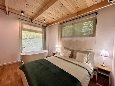 a bedroom with a bed and a bath tub and a window at Rogaty Domek przy Bobrowisku in Kornatka