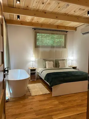 a bedroom with a bed and a bath tub at Rogaty Domek przy Bobrowisku in Kornatka
