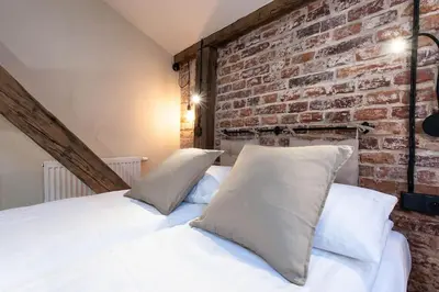 a bedroom with a brick wall and a bed with pillows at Studio apartment with an AC - Dietla 51 street in Kraków