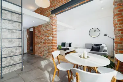 a room with a brick wall and a white table and chairs at Kazimierz District - Miodowa 32 Street in Kraków
