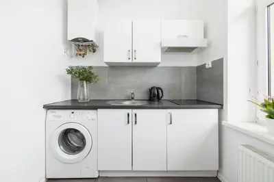 a white kitchen with a washing machine and a sink at 1-Bedroom Apartment with Balcony - Długa 65 in Kraków