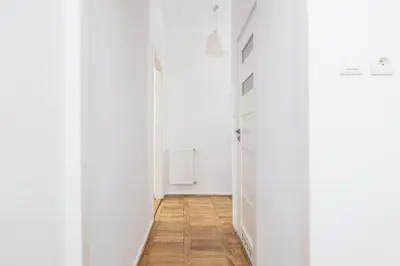 an empty hallway with white walls and a wooden floor at 1-Bedroom Apartment with Balcony - Długa 65 in Kraków