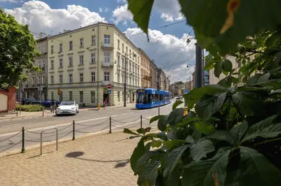 a blue bus driving down a city street with buildings at 1-Bedroom Apartment with Balcony - Długa 65 in Kraków