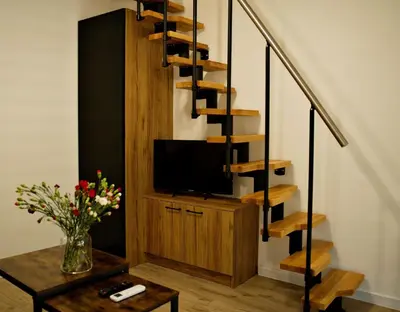 a living room with a tv and a spiral staircase at Nadwiślańska Apartments - Lipowa, 11km od Zator, Energylandia in Zator