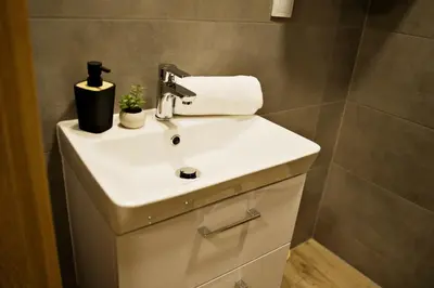 a bathroom with a white sink in a bathroom at Nadwiślańska Apartments - Lipowa, 11km od Zator, Energylandia in Zator
