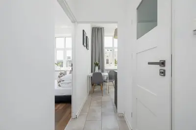 a white hallway with a dining room with a table at 2-Bedroom Apartment - Długa 65 in Kraków