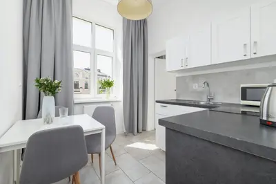 a kitchen with white cabinets and a table and chairs at 2-Bedroom Apartment - Długa 65 in Kraków