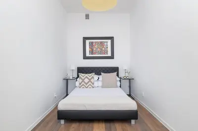 a bedroom with a bed with white walls and wood floors at 2-Bedroom Apartment - Długa 65 in Kraków