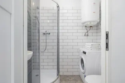 a white bathroom with a shower and a washing machine at 2-Bedroom Apartment - Długa 65 in Kraków