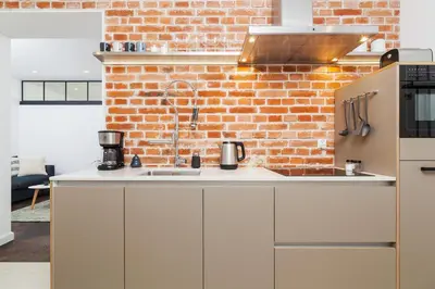 a kitchen with white cabinets and a brick wall at Karmelicka Street - Old Town in Kraków