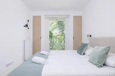 a white bedroom with two beds and a window at Krowoderska Apartment with Balcony near City Center by Rent like home in Kraków