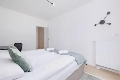 a white bedroom with a bed and a fan at Krowoderska Apartment with Balcony near City Center by Rent like home in Kraków