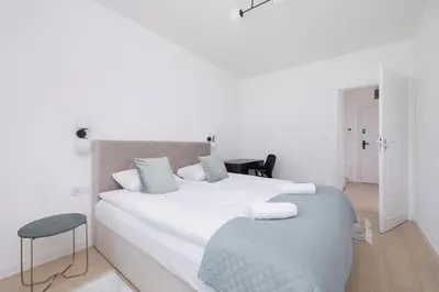 a white bedroom with a large bed with a chair at Krowoderska Apartment with Balcony near City Center by Rent like home in Kraków