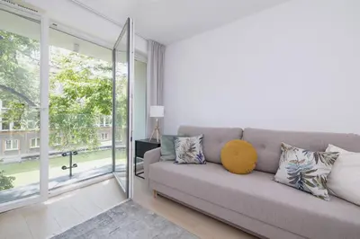 a living room with a couch and a large window at Krowoderska Apartment with Balcony near City Center by Rent like home in Kraków