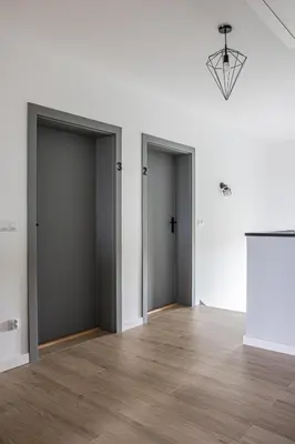 an empty room with three doors and a wooden floor at Noclegi Sunny House in Witanowice