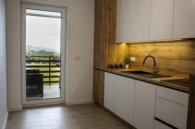 a kitchen with a sink and a door to a patio at Noclegi Sunny House in Witanowice