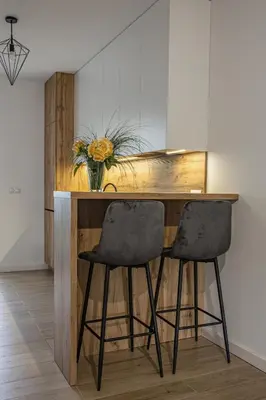 a kitchen with a wooden counter with two black bar stools at Noclegi Sunny House in Witanowice